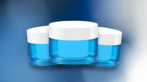 Three small, clear blue jars with white lids arranged in a triangular formation, set against a smooth gradient blue background.